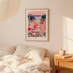 a bedroom scene with a framed poster of a colorful floral landscape hanging on the wall above a bed with striped pillows.