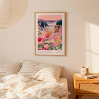 a bedroom scene with a framed poster of a colorful floral landscape hanging on the wall above a bed with striped pillows.