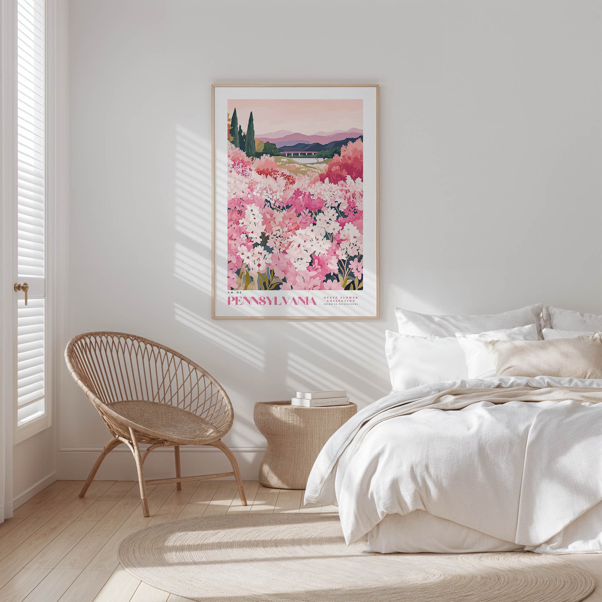 A bedroom with a large bed, a woven chair, and a framed poster of a field of pink flowers hanging on the wall.