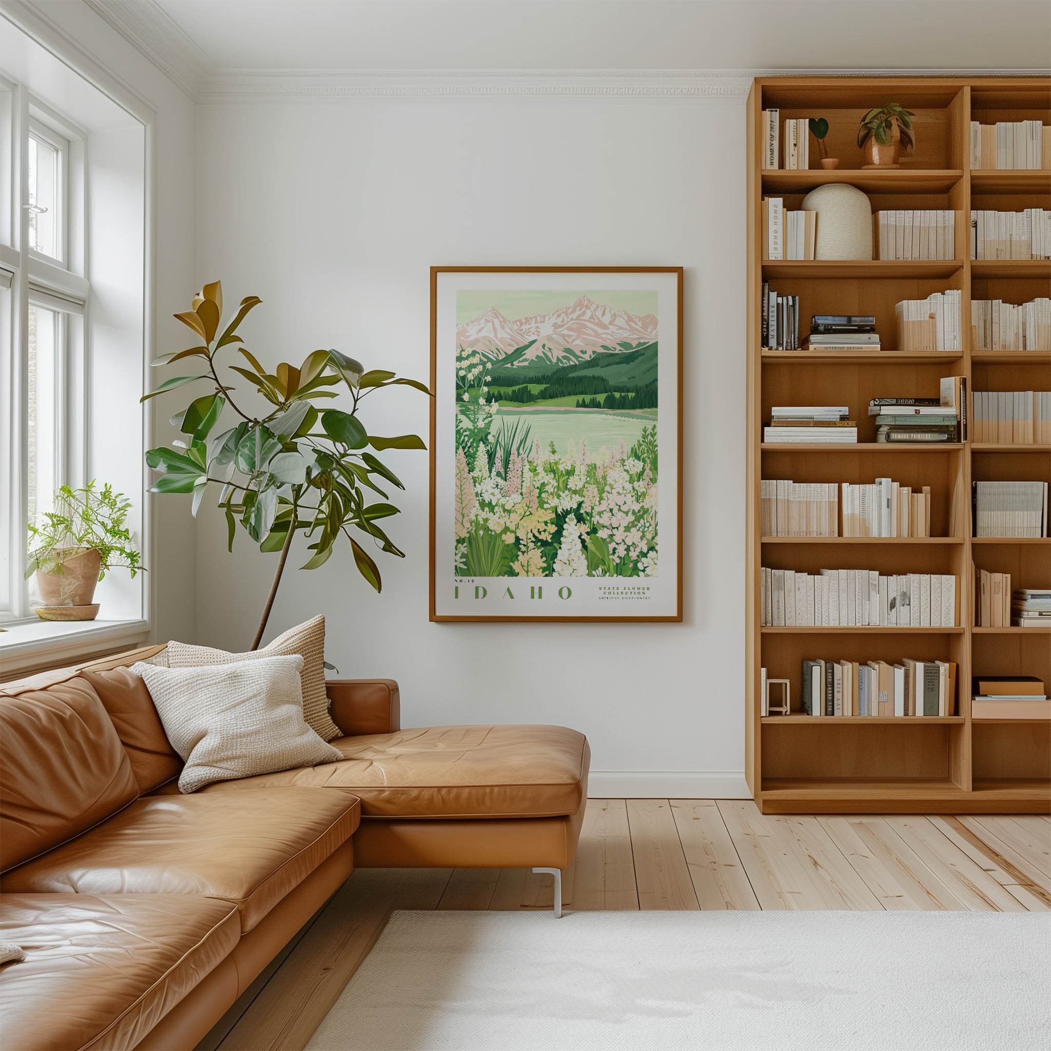a cozy living room with a large window, a comfortable leather sofa, a wooden bookshelf filled with books, and a framed poster of Idaho mountains hanging on the wall.