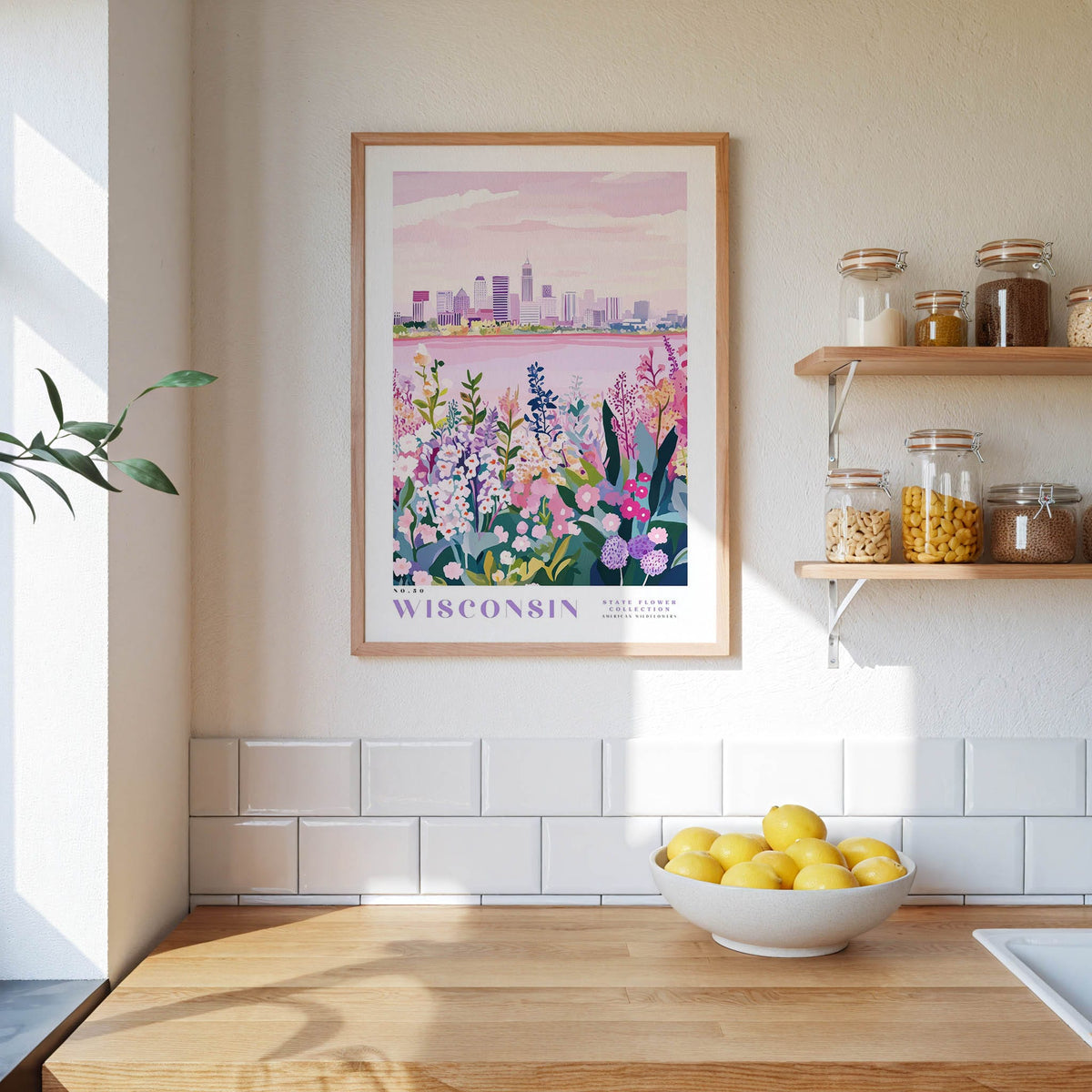 a framed poster of a cityscape with a lake in the background, hanging on a wall above a wooden counter with a bowl of lemons.
