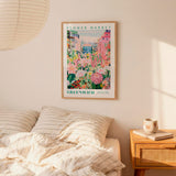 a bedroom setting with a framed poster of a flower market hanging on the wall above a bed with striped pillows.