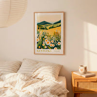 a bedroom scene with a framed poster of a field of flowers hanging on the wall above a bed with striped pillows.