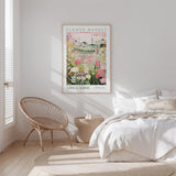 a bedroom with a bed, a woven chair, and a framed poster of a flower market in Adelaide hanging on the wall.