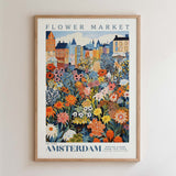 The image is a framed poster depicting a vibrant and colorful flower market in Amsterdam, with various flowers and plants in different shades of orange, pink, yellow, and green.