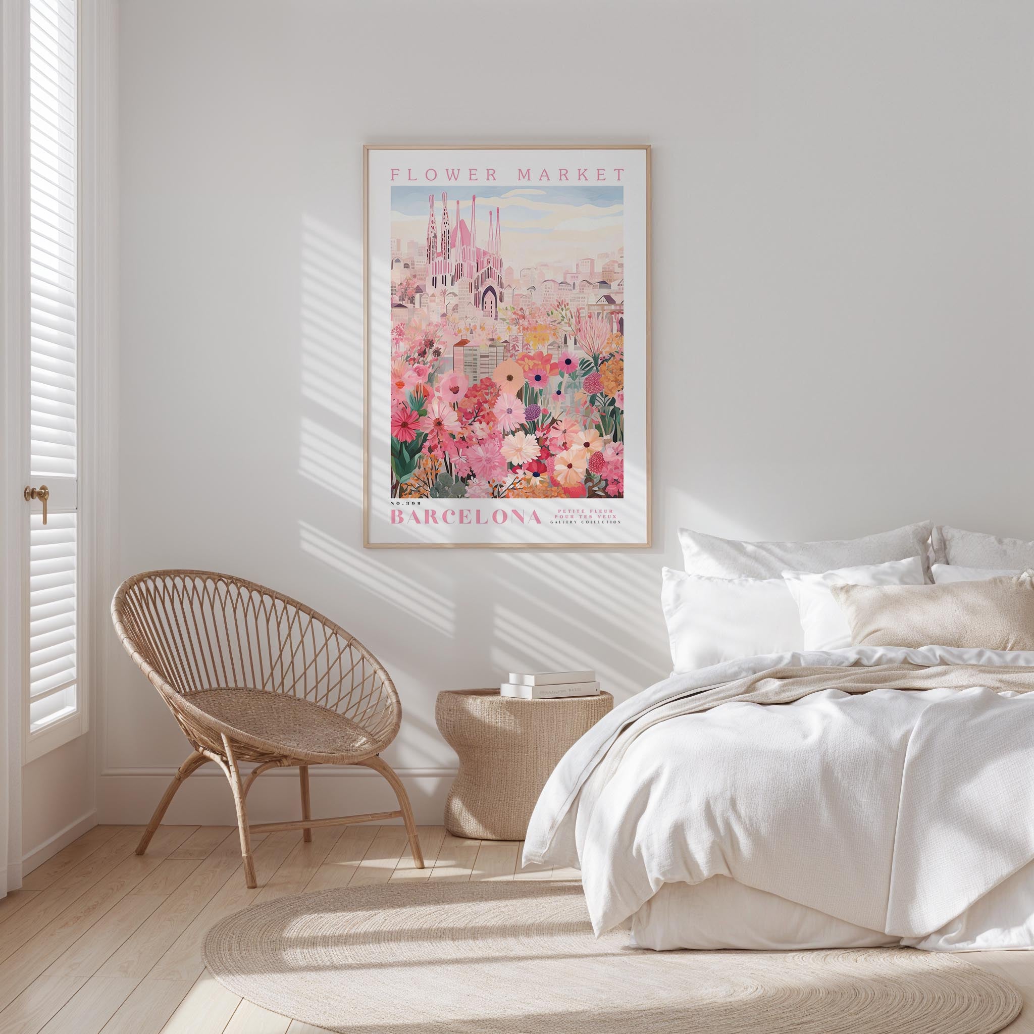 a bedroom with a large poster of the Barcelona Flower Market hanging on the wall. The poster features a colorful illustration of the market with various flowers and buildings. The room has a white bed, a woven chair, and a small side table. The overall color scheme of the room is predominantly white and beige, creating a serene and calming atmosphere.