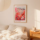 a bedroom setting with a framed poster of a flower market hanging on the wall above a bed with striped pillows.