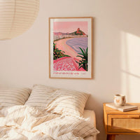 a framed poster of Copacabana Beach hanging on a wall above a bed with striped pillows.