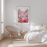 a bedroom with a bed, a wicker chair, and a framed poster of a flower market in the background.