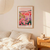 a bedroom scene with a framed poster of a colorful landscape hanging on the wall above a bed with striped pillows.