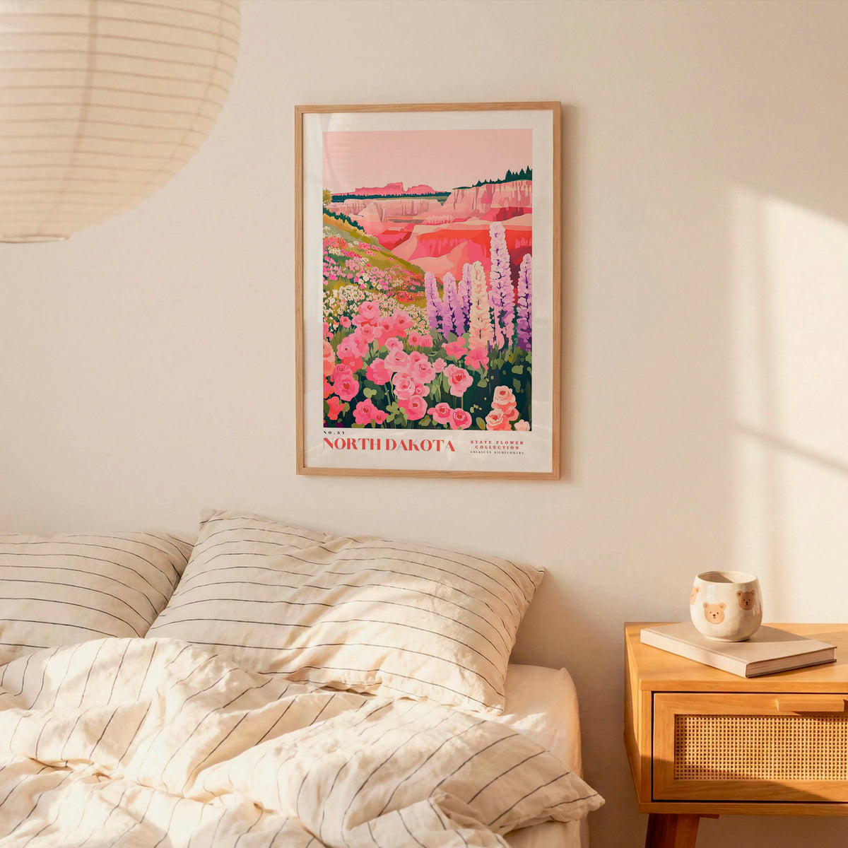 a bedroom scene with a framed poster of a colorful landscape hanging on the wall above a bed with striped pillows.