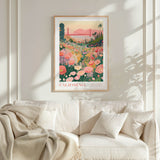a framed poster of a vibrant garden scene with a bridge in the background, hanging on a wall above a white couch with a blanket draped over it.