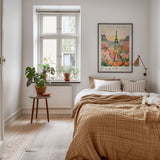 a cozy bedroom with a large bed, a nightstand with a plant, and a framed poster of Paris on the wall.