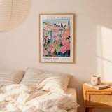 a bedroom setting with a framed poster of a colorful floral scene hanging on the wall above a bed with striped pillows.