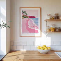 a kitchen counter with a bowl of lemons, a framed poster of a beach, and a shelf with jars and bottles.