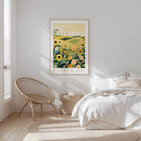 a serene bedroom scene with a bed, a woven chair, and a framed poster of a field of flowers hanging on the wall.
