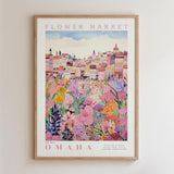 The image is a framed poster depicting a colorful and vibrant cityscape with a variety of flowers and plants in the foreground.