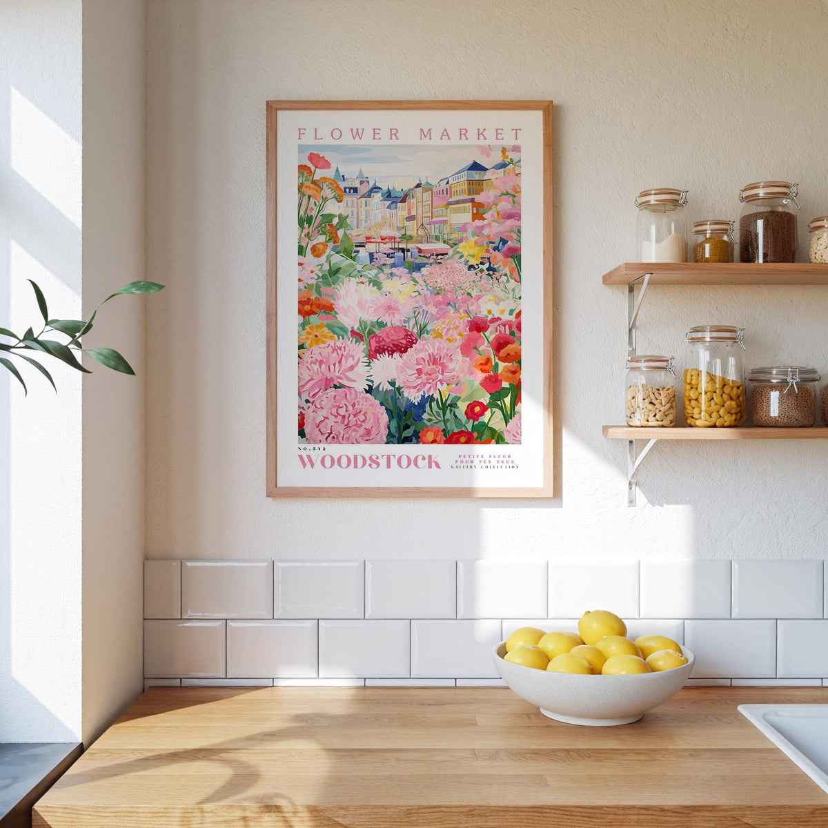 a kitchen counter with a bowl of lemons, a framed poster of a flower market, and shelves with jars and containers.