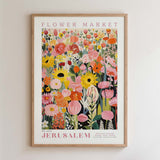 The image is a framed poster depicting a vibrant and colorful floral arrangement, with various types of flowers and foliage. The poster is titled "FLOWER MARKET" and "JERUSALEM" and is framed with a wooden border.