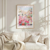 a framed poster of a flower market, with a white sofa and a blanket in the foreground.