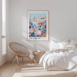 a bedroom with a large poster of a flower market on the wall, a woven chair, and a bed with white bedding.