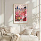 a framed poster of a flower market in Edinburgh, Scotland, with a cityscape in the background.