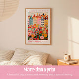 a poster of a colorful cityscape of Amsterdam, hanging on a wall above a bed with striped pillows.