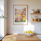 a kitchen scene with a framed poster of a flower market in Nantucket hanging on the wall above a wooden counter. On the counter, there is a bowl of lemons and a plant.
