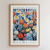The image is a framed poster of a flower market in Miami, featuring a vibrant and colorful illustration of various flowers and plants.